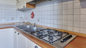 A kitchen with white cabinets, a stainless steel sink, and a gas stove. - Apartment 'Tramonto' with Private Terrace, Wi-Fi and Air Conditioning (Capoliveri)