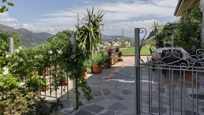 A stone pathway leading to a gate, surrounded by potted plants and a view of mountains. - Apartment 'Tramonto' with Private Terrace, Wi-Fi and Air Conditioning (Capoliveri)