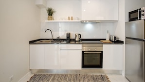 A modern kitchen with white cabinets, a stainless steel range, a built-in oven, and a microwave.