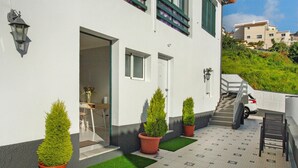 A building with a white exterior, a door, a staircase, and potted plants.