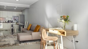 A modern living room with a sofa, a wooden desk, and a vase with flowers.