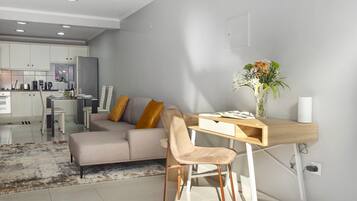 Een moderne woonkamer met een bank, een houten bureau en een vaas met bloemen.