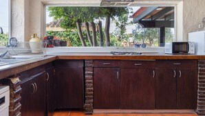 Uma cozinha com uma janela grande, armários de madeira escura, micro-ondas e fogão a gás.