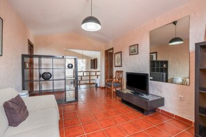 Un salon avec un canapé, un téléviseur et une chaise en bois.