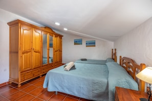 Une chambre avec deux lits, une armoire en bois et une petite table avec une lampe.