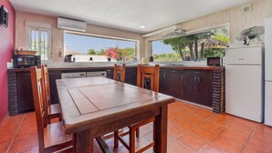 Cozinha com mesa de jantar, cadeiras, geladeira e janela com vista para o verde.