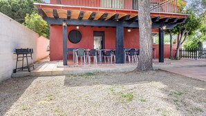 Um edifício de dois andares com fachada vermelha, varanda, área de estar externa e churrasqueira.