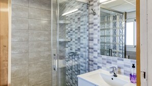 A modern bathroom with a glass-enclosed shower, a white sink, and a tiled backsplash. - Apartment 'Marval' with Sea View, Wi-Fi and Air Conditioning (Llançà)