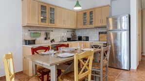 Une cuisine avec des meubles en bois, un réfrigérateur en acier inoxydable et une table à manger avec des chaises.