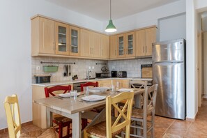 Une cuisine avec des meubles en bois, un réfrigérateur en acier inoxydable et une table à manger avec des chaises.