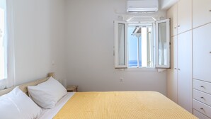 Une chambre à coucher comprenant un lit, une fenêtre donnant sur un paysage dégagé, une armoire et un appareil de climatisation.