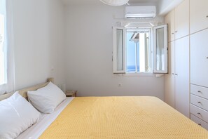 Une chambre à coucher comprenant un lit, une fenêtre donnant sur un paysage dégagé, une armoire et un appareil de climatisation.