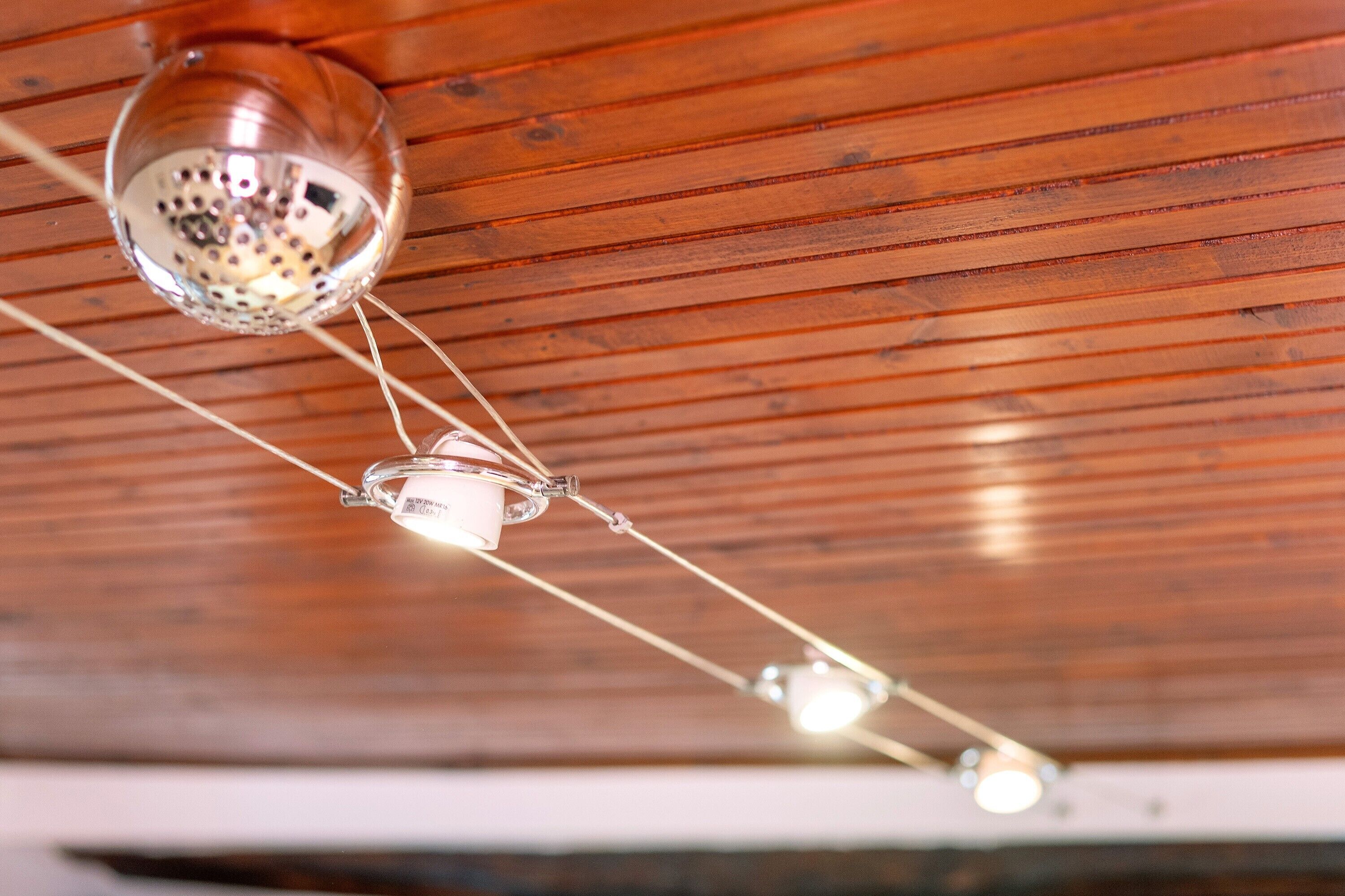 Un plafond avec des lambris en bois et des suspensions lumineuses.