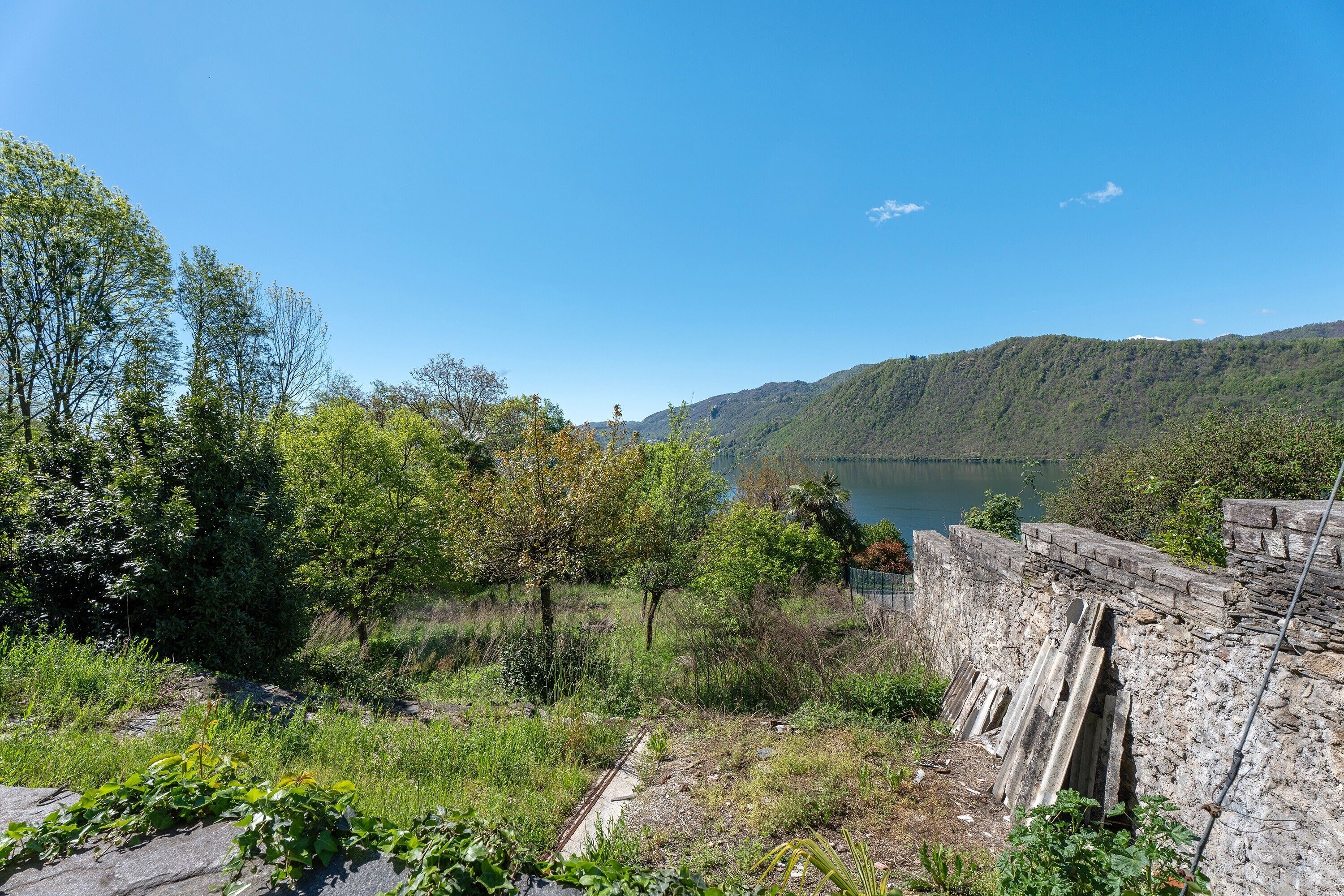 A natural landscape with a body of water, trees, and a stone wall.