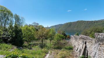 A natural landscape with a body of water, trees, and a stone wall.