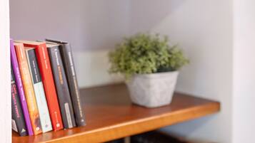 Una estantería de madera con una fila de libros y una planta en maceta.