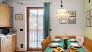 A dining area with a table set for two, a bottle of champagne, and a variety of food. - Villa 'Enrica' with Mountain View, Private Terrace and Wi-Fi (Primiero San Martino di Castrozza)