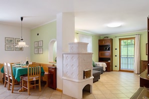 A dining area with a table set for four, a white stove, and a sofa in a room with green walls and a window.