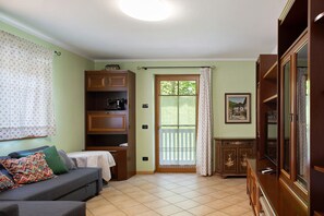 A living room with a sofa, wooden cabinets, a television, and a sliding glass door leading to an outdoor area.
