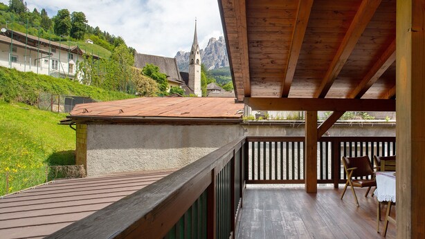 A wooden deck with a view of a church and mountains. - Villa 'Enrica' with Mountain View, Private Terrace and Wi-Fi (Primiero San Martino di Castrozza)