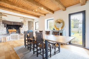A dining area with a wooden table and chairs, a stone fireplace, and a large mirror.