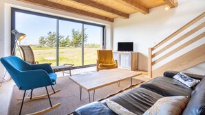 Ein modernes Wohnzimmer mit einer Couch, einem Schaukelstuhl, einem Tisch und einem Fernseher.