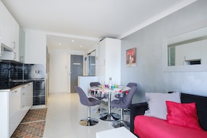 A modern kitchen with a dining area, a sofa, and a mirror on the wall. - Apartment 'Les Pins' with Sea View, Wi-Fi and Air Conditioning (Cannes)