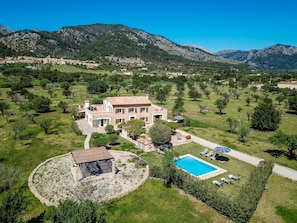 Une grande maison avec une piscine, entourée d’une pelouse bien entretenue et d’arbres.