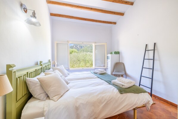 Une chambre avec un lit, une fenêtre, une échelle et une chaise.