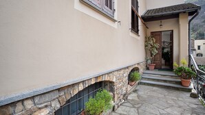 Un edificio con fachada de piedra, puerta de madera y macetas con plantas en los escalones.
