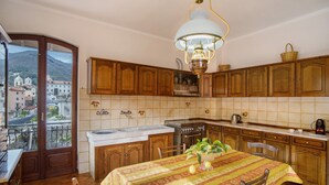 Una cocina con armarios de madera, una mesa de comedor con mantel y vistas a través de una puerta de cristal.