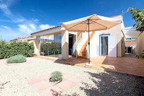 Une maison moderne dotée d’un patio, d’un espace de détente extérieur abrité et d’un escalier menant à l’étage supérieur.