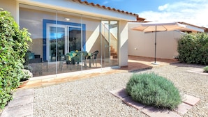 Una casa moderna con puerta de cristal, mobiliario exterior y zona de patio.