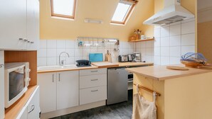 A modern kitchen with white cabinets, a dishwasher, a microwave, and a window above the sink.