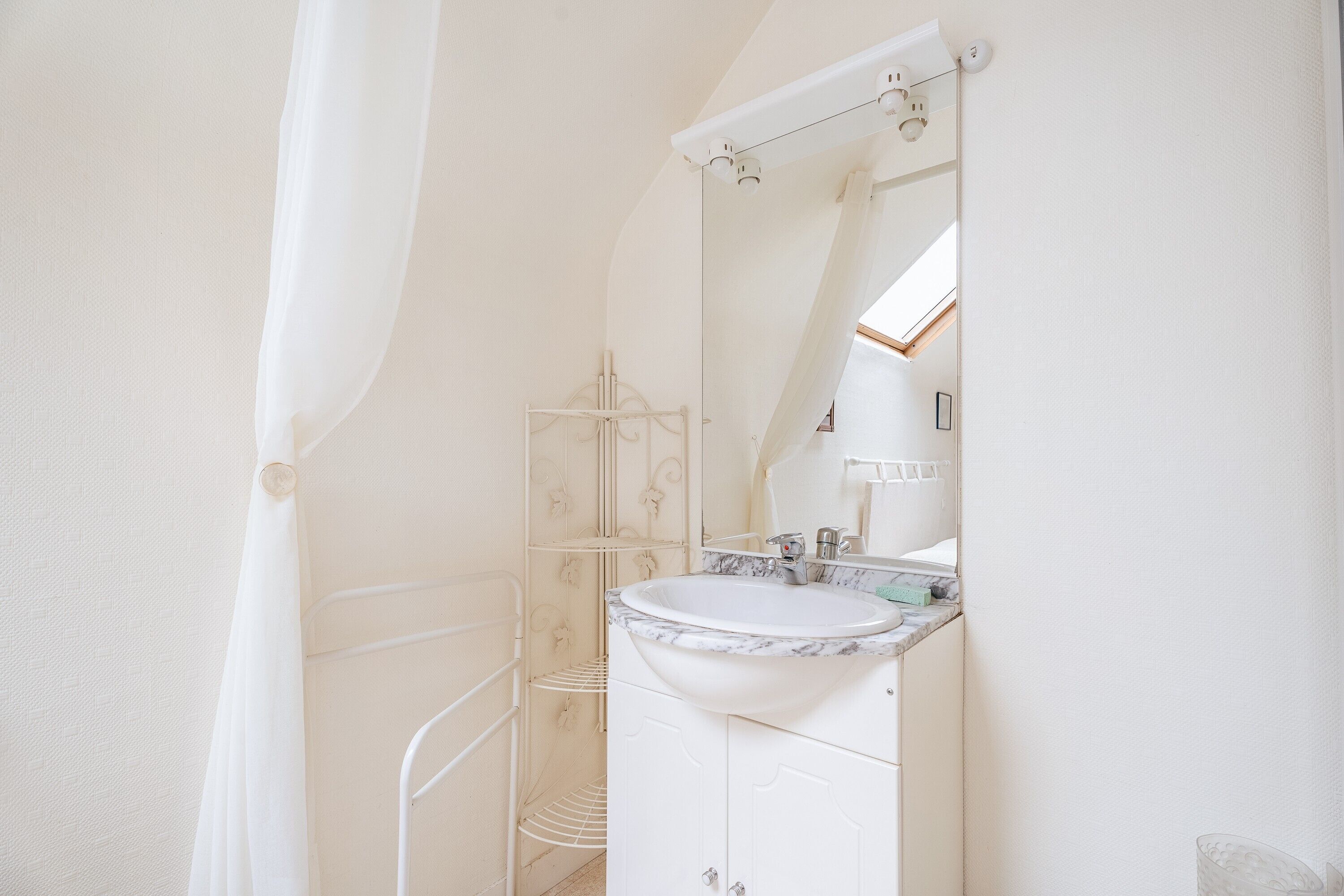 A bathroom with a white sink, mirror, and shower area.