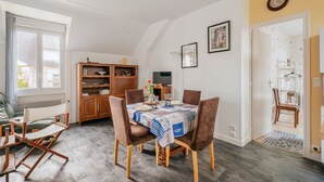 A dining area with a table set for four, a wooden cabinet, and a television.