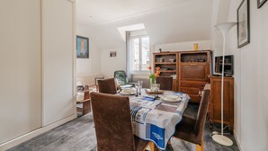 A dining area with a table set for four, a bookshelf, and a large window.