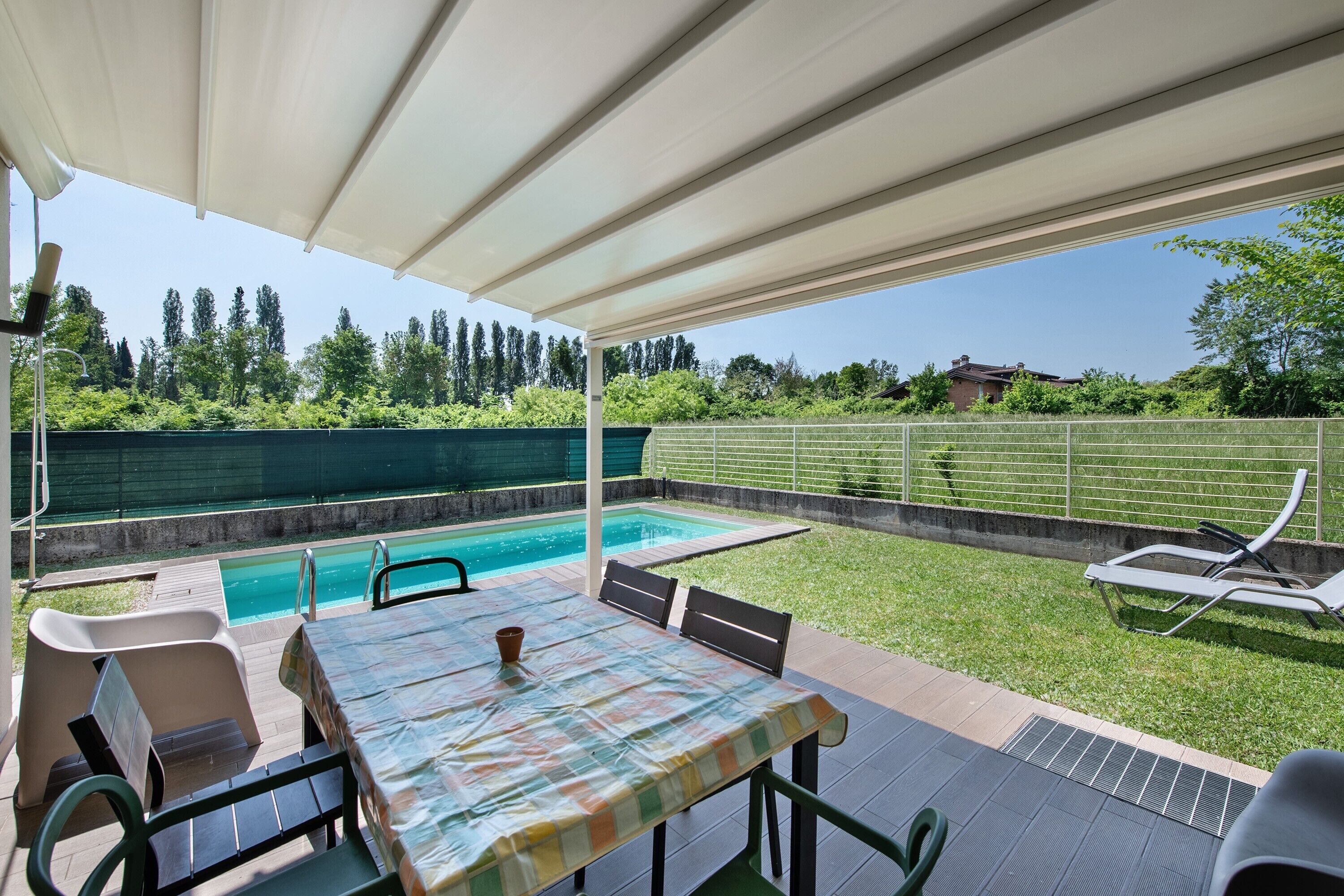An outdoor patio with a pool, a table, and lounge chairs.