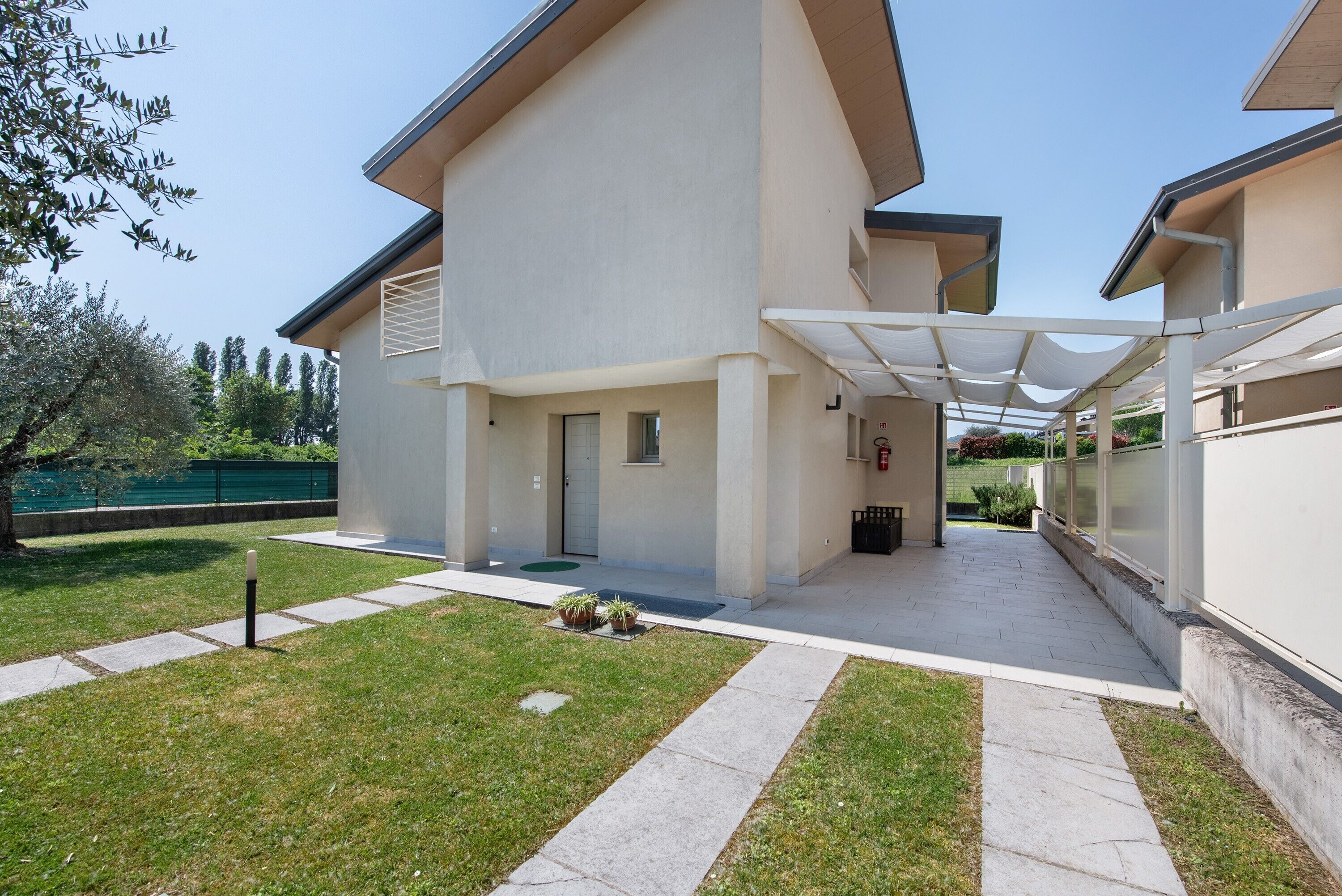 A modern building with a covered entrance, a grassy lawn, and a clear sky.