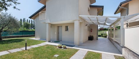 A modern building with a covered entrance, a grassy lawn, and a clear sky.