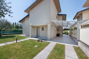 Un bâtiment moderne doté d’un porche, d’une pelouse verdoyante et surplombé d’un ciel dégagé.
