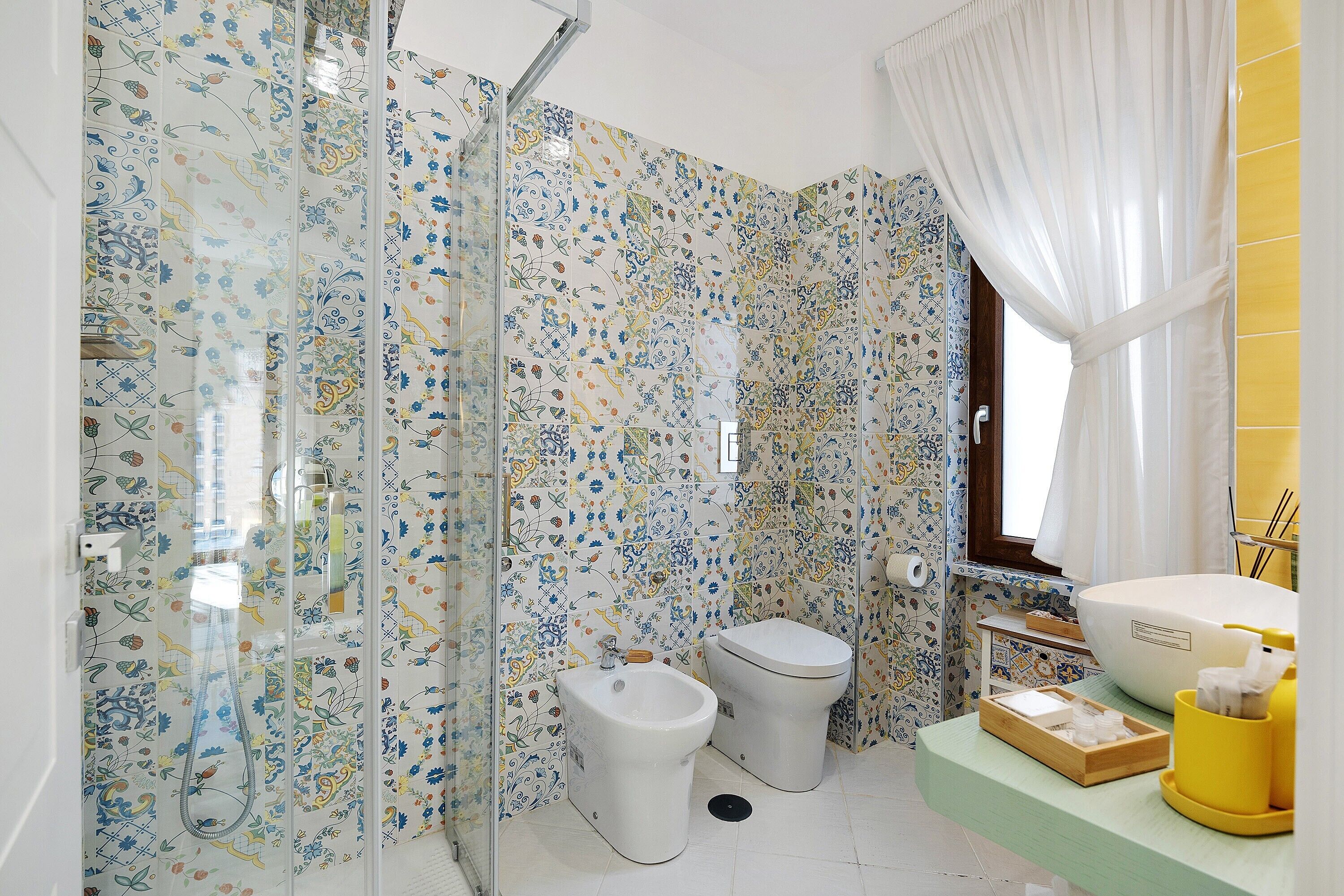 A bathroom with a shower, bidet, toilet, and a sink with a yellow soap dispenser.