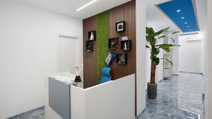 Un área de recepción con diseño moderno, que incluye un mostrador de recepción, una pared verde y un techo azul.