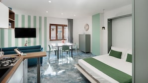 A hotel room with a bed, a desk, a dining table, and a TV. - Apartment 'Monolocale A Due Passi Dagli Scavi' with Mountain View, Wi-Fi and Air Conditioning (Ercolano)