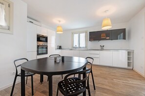 Une cuisine moderne avec des meubles blancs, une table à manger noire et deux suspensions.