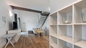 A modern interior with a staircase, a sofa, a TV, and white shelving units. - Villa 'Le Golfette Ville Al Golf 2' with Private Pool, Private Terrace and Wi-Fi (Manerba del Garda)