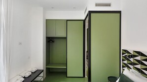 A hotel room with a bed, a green wardrobe, a bench with towels, and a small table. - Apartment 'Superior In Via Toledo' with Balcony, Wi-Fi and Air Conditioning (Napoli)