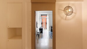 A hallway with a ceiling light fixture, a door, and a view into a room with a patterned floor and a table. - Apartment 'Deluxe In Via Toledo' with Balcony, Wi-Fi and Air Conditioning (Napoli)