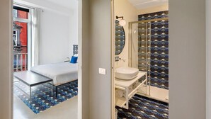 A bedroom with a bed, a small table, and a view of a red building outside. - Apartment 'Deluxe In Via Toledo' with Balcony, Wi-Fi and Air Conditioning (Napoli)