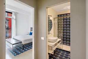 Une chambre à coucher avec un lit, une petite table et une vue sur un bâtiment rouge à l’extérieur.